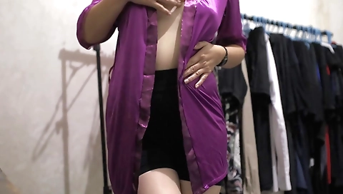 Sexy girl in a black satin dress tries on a black lingerie